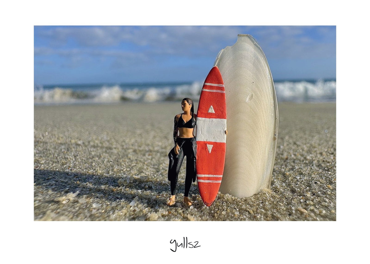 Œuvre photographique d'une surfeuse en combinaison adossée à un os de seiche en Baie de Quiberon.